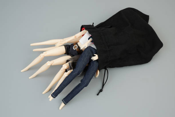istock Many female dolls in black sack on gray background. 2183499761