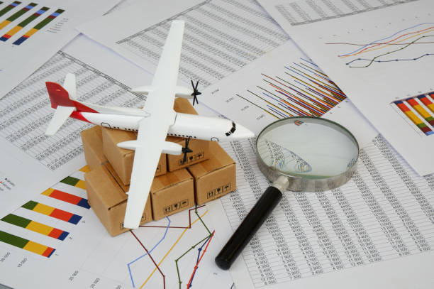 istock Airplane on shipping carton boxes under magnifying glass on financial reports. 2183499868