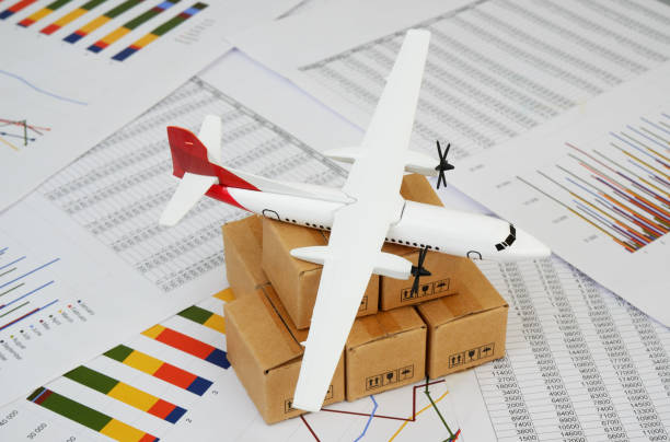 Airplane on shipping carton boxes on financial documents close up. Shipment and transportation concept.