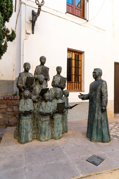 A bronze statue of a choir conductor with singers holding sheet music, serving as a monument in Guadix, Spain.