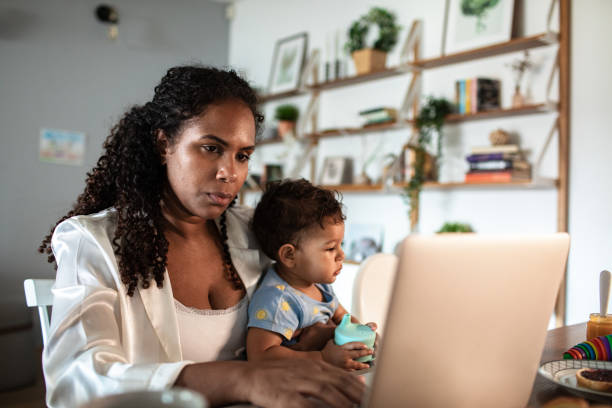 istock Young mother and son having breakfast together while the mother is working on her laptop 2183502271