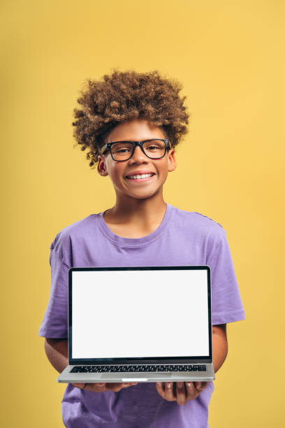 istock Happy, smart African American boy wearing eyeglasses, holding laptop with empty screen white display 2183503949