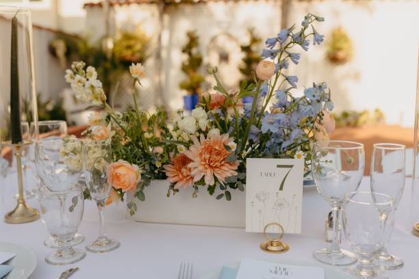istock Floral centerpiece featuring peach, yellow, blue, and white flowers in a rectangular vase. 2183511392