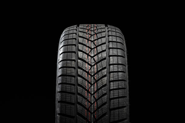 istock Winter car tire standing on black background showing tread pattern 2183511925