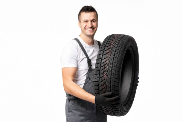 istock Mechanic holding winter tire smiling on white background 2183511988