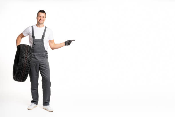 istock Mechanic holding tire and pointing to white background 2183512047