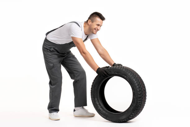 istock Mechanic pushing large tire on white background 2183512051