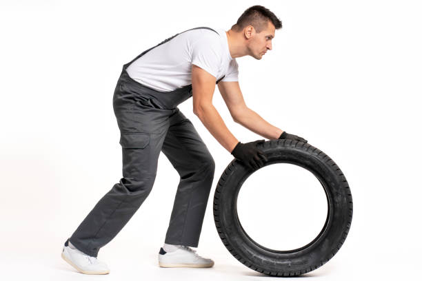 istock Mechanic pushing large tire on white background 2183512064