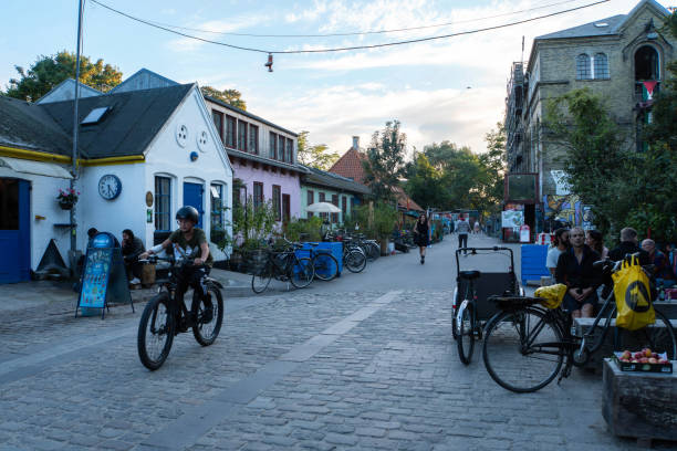Copenhagen, Denmark - September 21, 2024: People walking and cycling by the colorful buildings of Freetown Christiania.