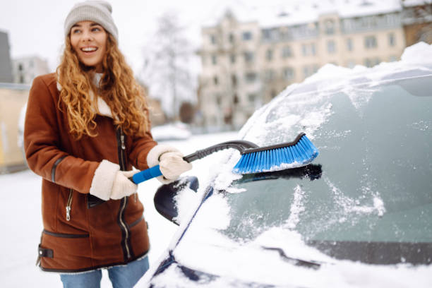 istock Woman cleaning snow from car windshield. Scraping ice. 2183525035