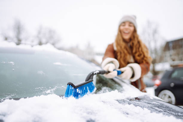 istock Woman cleaning snow from car windshield. Scraping ice. 2183525039