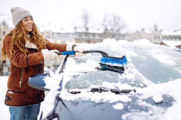istock Woman cleaning snow from car windshield. Scraping ice. 2183525072