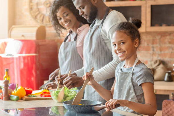 istock Smiling girl helping parents cooking dinner in kitchen 2183526675