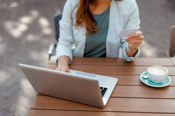 istock Woman using credit card with laptop at cafe table. 2183537354