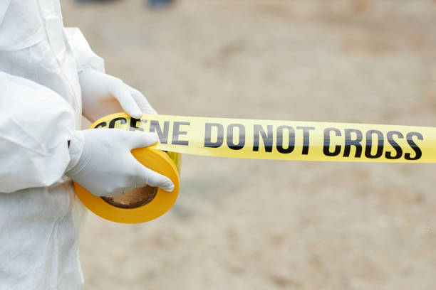 istock Man in Hazmat Gear Unrolling Warning Tape 2183538601