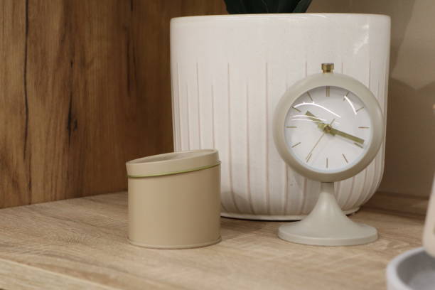 istock A modern clock alongside a decorative container beautifully displayed on a wooden surface 2183541148