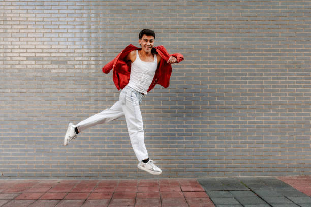 istock Latin LGBT young man jumping with red jacket and white outfit 2183544336