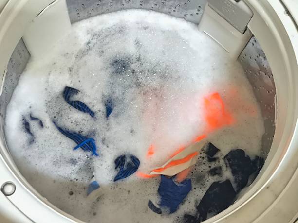 istock Dirty clothes spinning in a top-loading washing machine. Laundry and house keeping concept 2183547162
