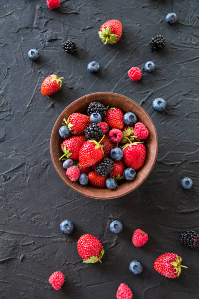 Different fresh ripe berries and mint on table outdoors, space for text