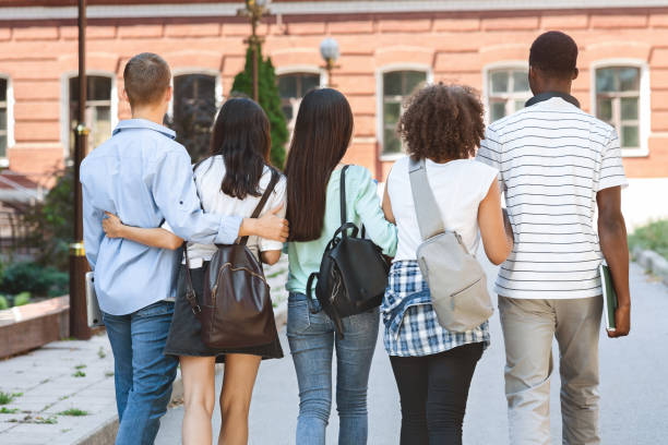 istock Happy College Friends Walking In Campus And Smiling To Camera 2183552904