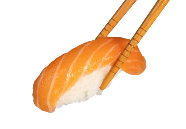 Fresh salmon nigiri sushi is being held by chopsticks, isolated on a white background
