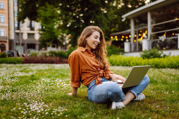 istock Young Woman sitting on grass ground, working on laptop. 2183558621