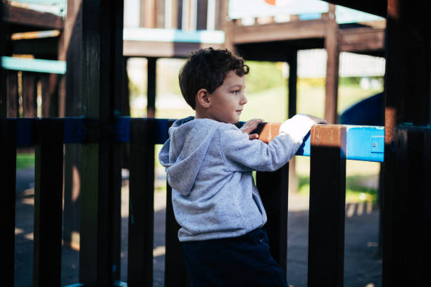 istock Thoughtful Young Boy Pausing at the Playground Fence 2183560448