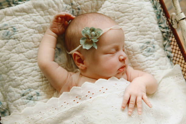 A newborn baby girl sleeps in a small bed with cozy quilts.