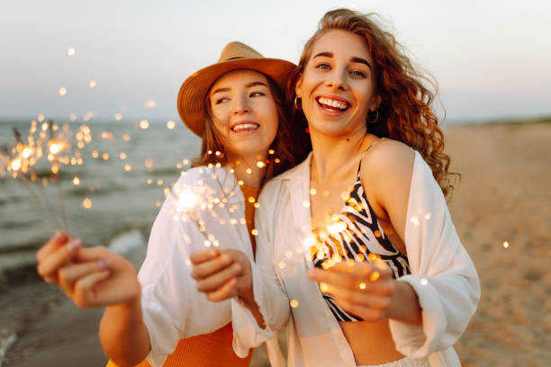 istock Beautiful Two women holding sparkler celebration on beach. 2183562911