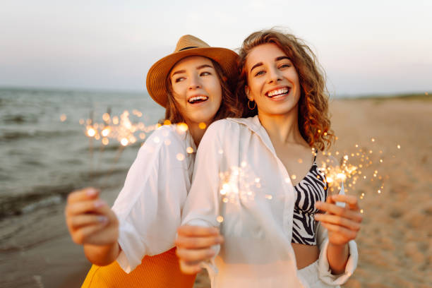 istock Beautiful Two women holding sparkler celebration on beach. 2183562917