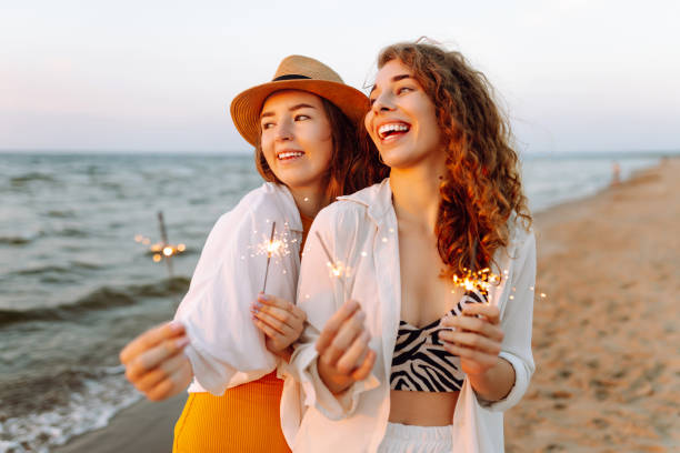 istock Beautiful Two women holding sparkler celebration on beach. 2183562938