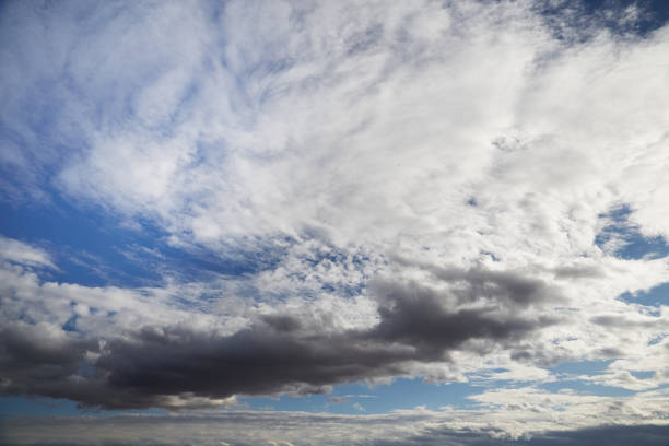 White and gray clouds in a blue sky, variable cloudiness, selective focus, heavenly background, celestial landscape.