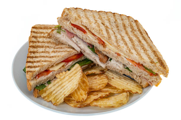 Chicken club sandwich on a plate with potato crisps - white background