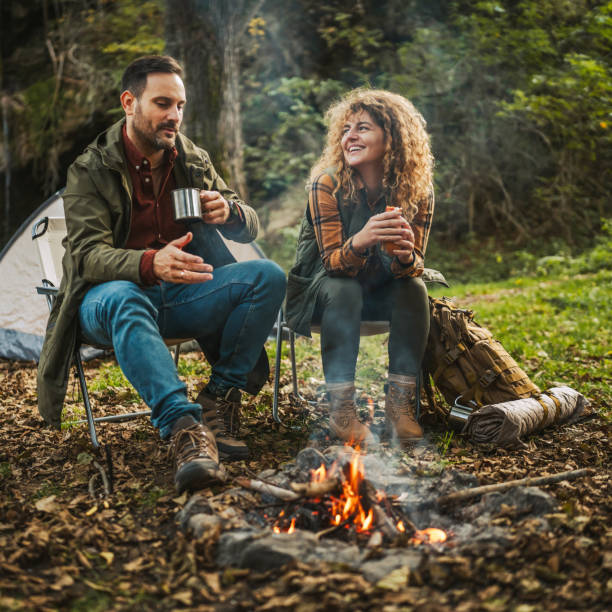 istock couple eat hot dogs and warm themselves in front campfire 2183583079