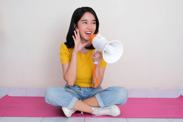 istock A women sitting cross legged on the floor telling something using megaphone 2183596514