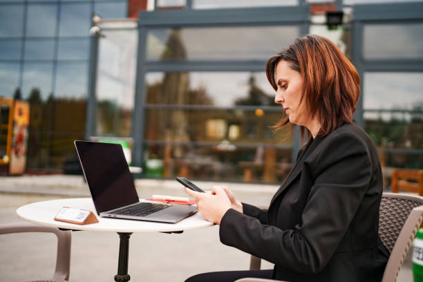 istock Business Woman using laptop and mobile phone in a sidewalk cafe. 2183600903