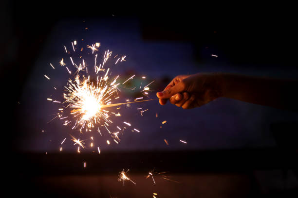 A vibrant sparkler bursts into life, lighting up the night with a dazzling shower of golden sparks.