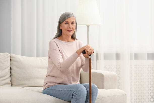 istock Mature woman with walking cane on sofa at home 2183608148