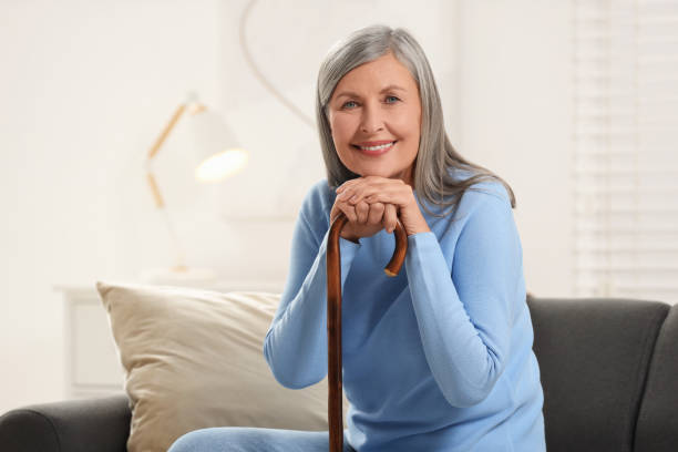 istock Mature woman with walking cane on sofa at home 2183608152