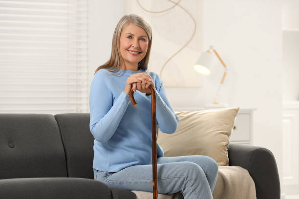 istock Mature woman with walking cane on sofa at home 2183608219