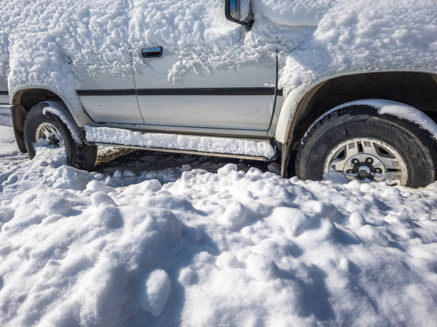 istock snow covered white SUV car at sunny white winter day 2183608977