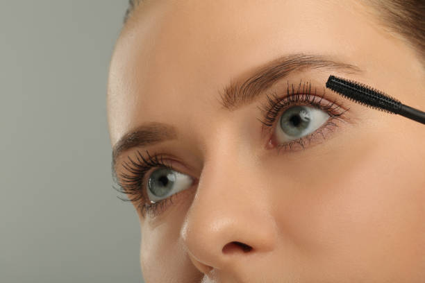 istock Woman applying mascara on grey background, closeup 2183609588