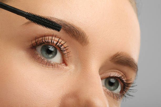 istock Woman applying mascara on grey background, closeup 2183609707