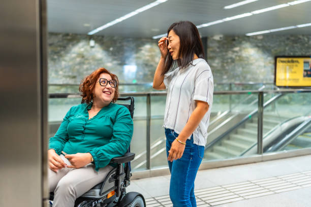 istock Smiling disabled woman and friend talking waiting for subway elevator 2183622027