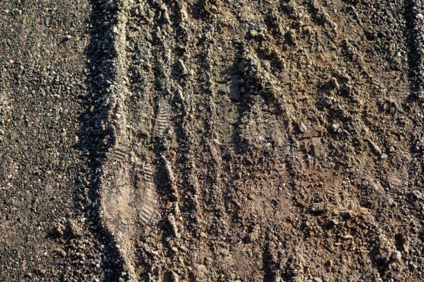 Gravel ground road surface with car wheel imprint. Background and texture.