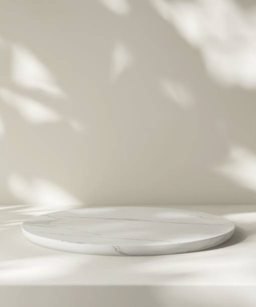 Modern round white marble podium table on cream counter in dappled sunlight, leaf foliage shadow on wall for luxury organic fashion, beauty, cosmetic, skincare, body care product display background 3D