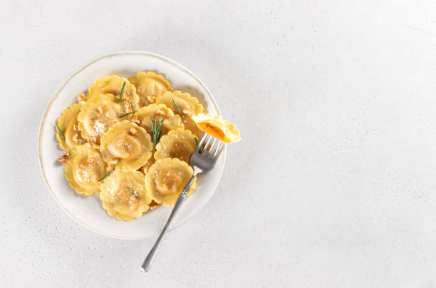 istock Ravioli pasta filled with pumpkin, nuts and fresh herbs on white background. Copy space. 2183625539