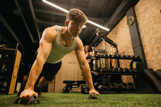 istock Focused man doing push-ups in a modern gym environment. 2183625808