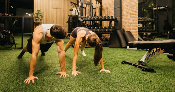 istock Couple performing plank exercises together in a modern gym environment. 2183625913