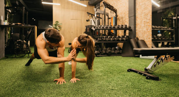 istock Couple performing push-up exercise together in modern gym with enthusiasm 2183625940